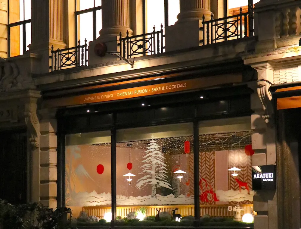Akatuki's windows on Great Queen Street dressed for Christmas: a snowy pine, red lanterns and deer.